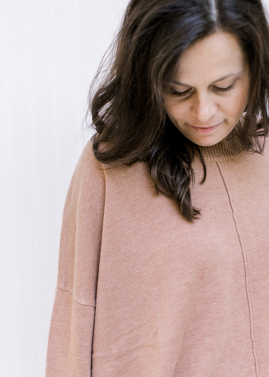 Close up of front seam detail on a sienna colored sweater with long sleeves and ribbed detail. 