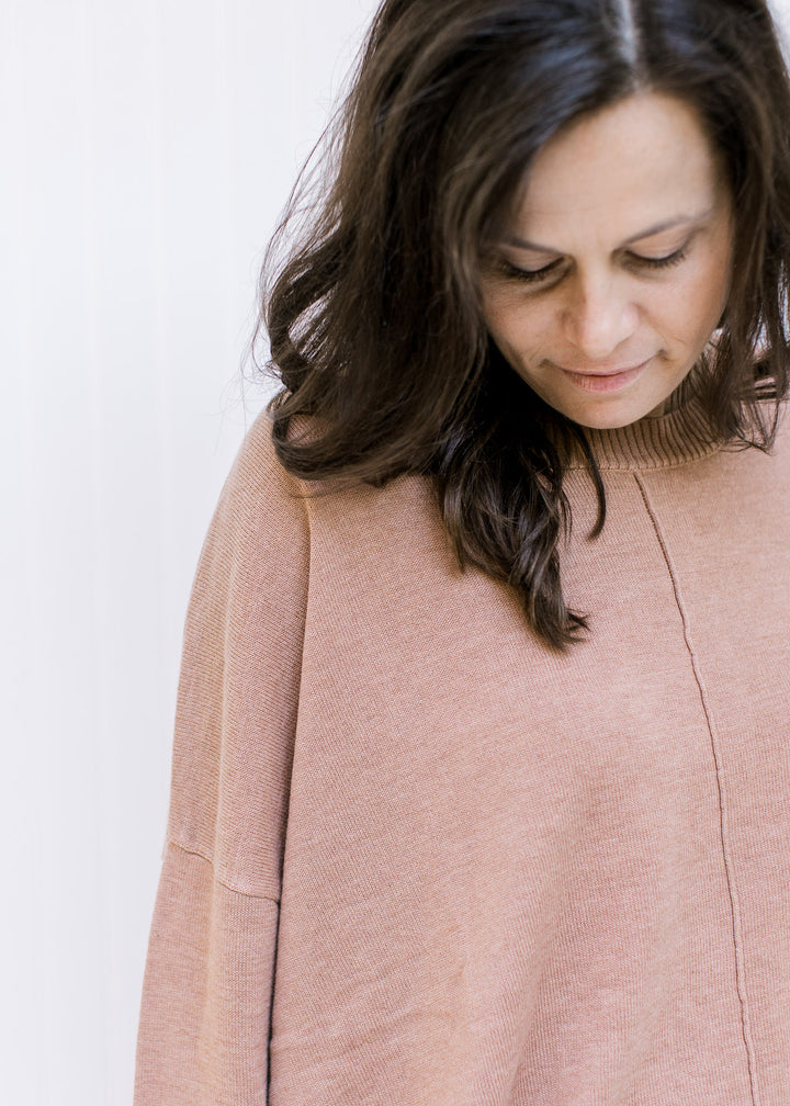 Close up of front seam detail on a sienna colored sweater with long sleeves and ribbed detail. 