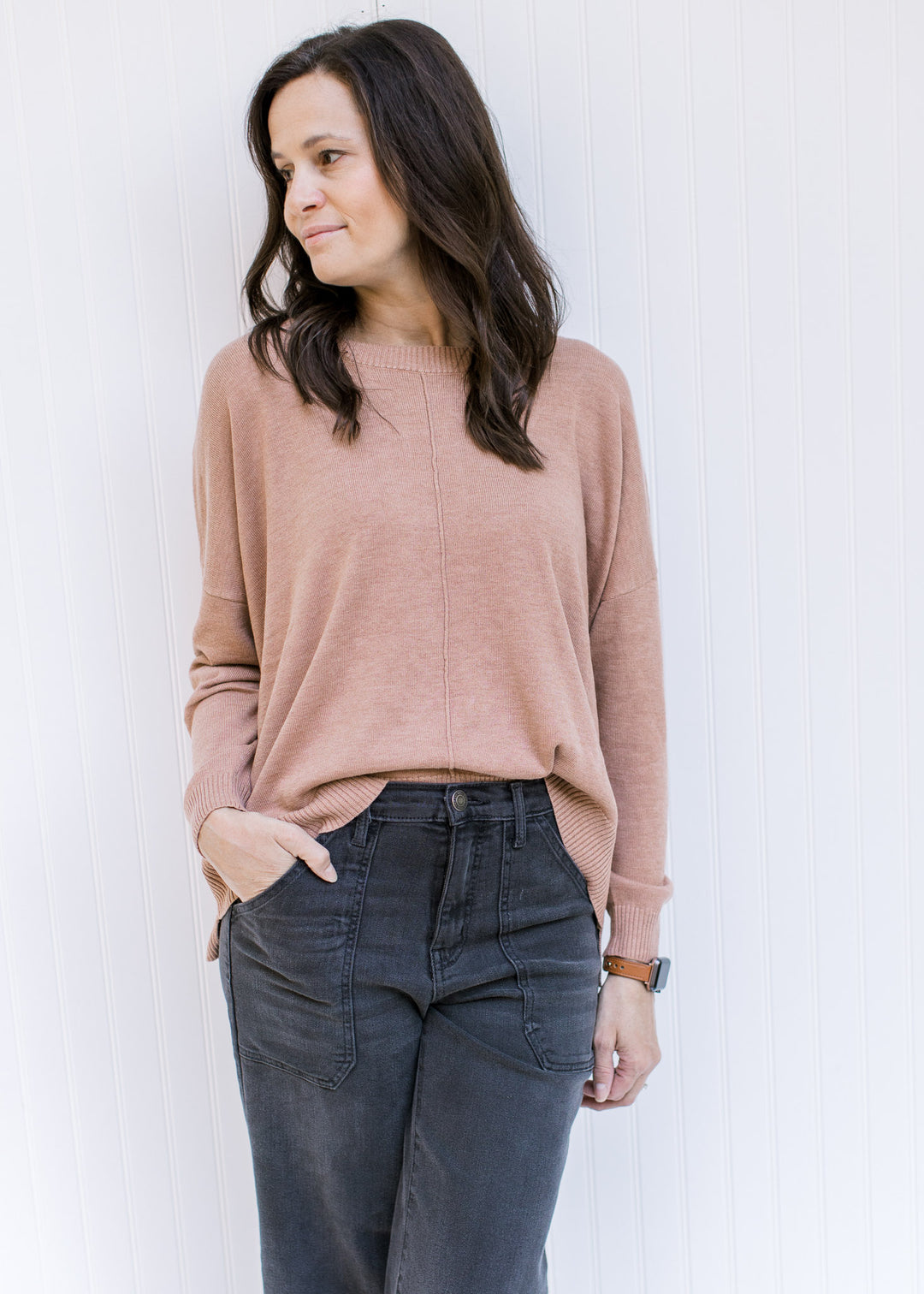 Model wearing jeans with a camel colored sweater with a front hem detail and long sleeves. 
