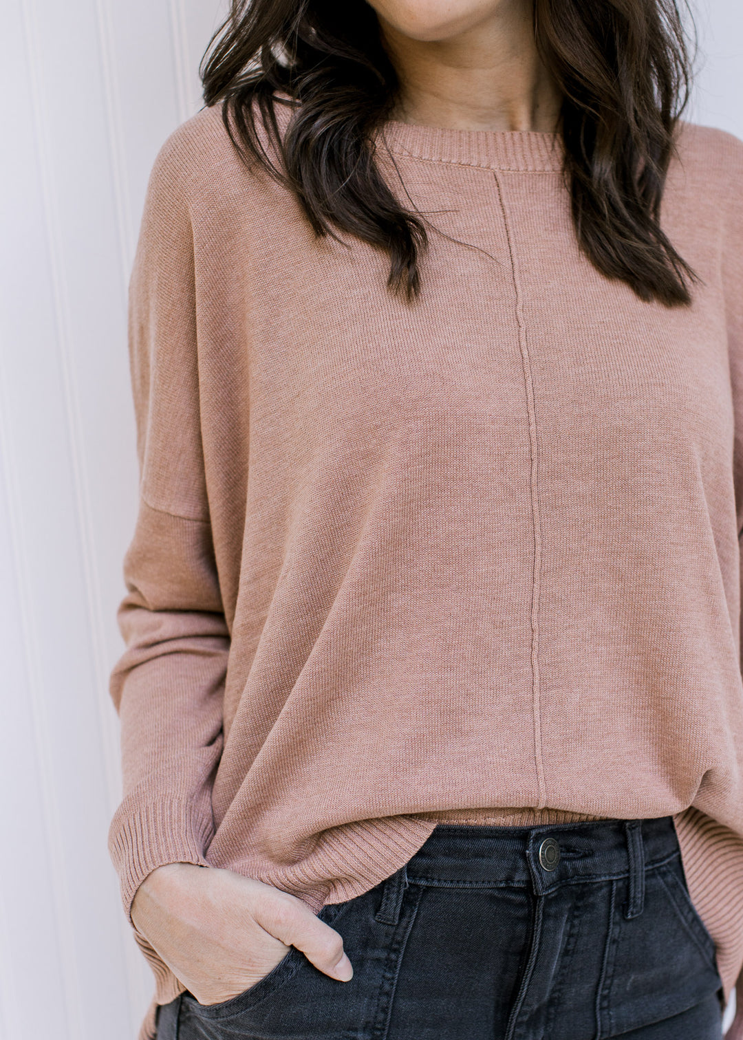 Model wearing a camel colored sweater with a front hem detail, long sleeves and a round neck.