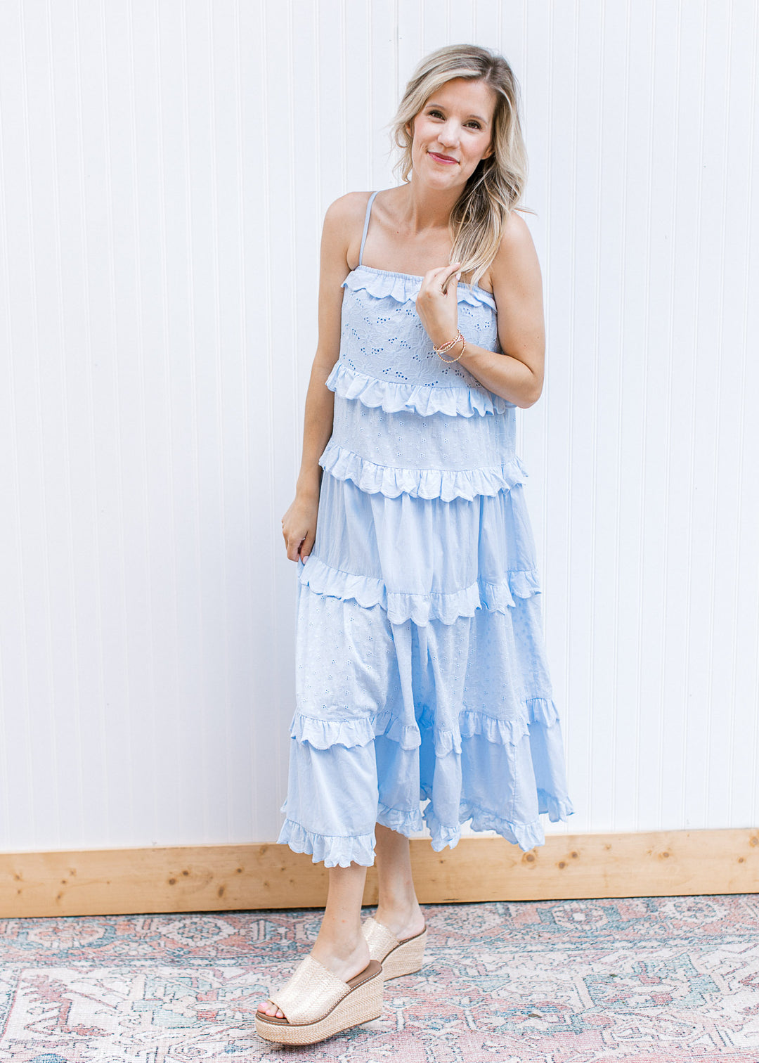 Model wearing wedges and a pale blue midi with floral eyelets, ruffle tiers and spaghetti straps. 