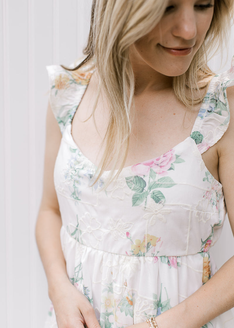 Close up of sweetheart neck and ruffle sleeve on a white midi with bright floral and elastic wasit.