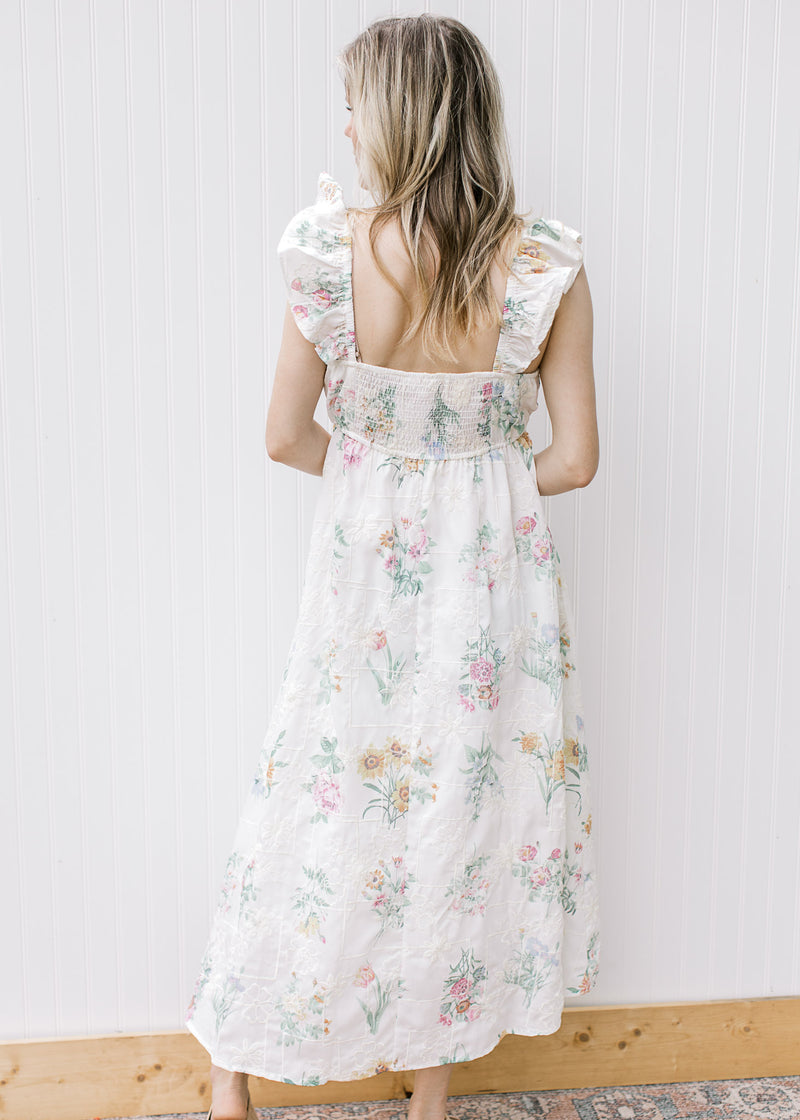 Model wearing a white midi with tone one tone embroidery, bright flowers and a smocked back.