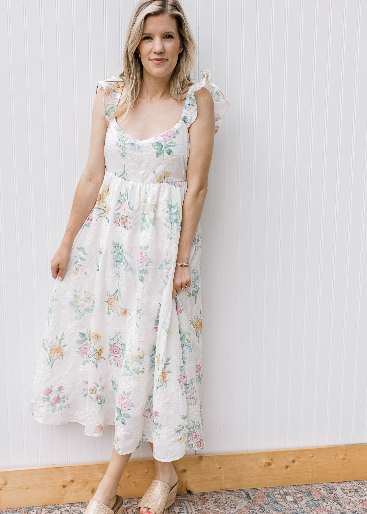 Model wearing a white midi with tone one tone embroidery and bright flowers and a sweetheart neck.