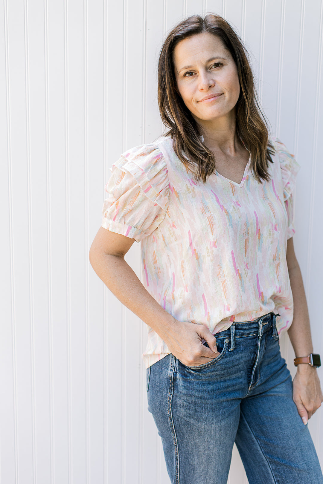 Model wearing an abstract v-neck top with short puff sleeves and a v-neck.
