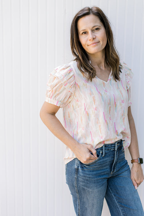 Model wearing an abstract v-neck top with short puff sleeves and a v-neck.