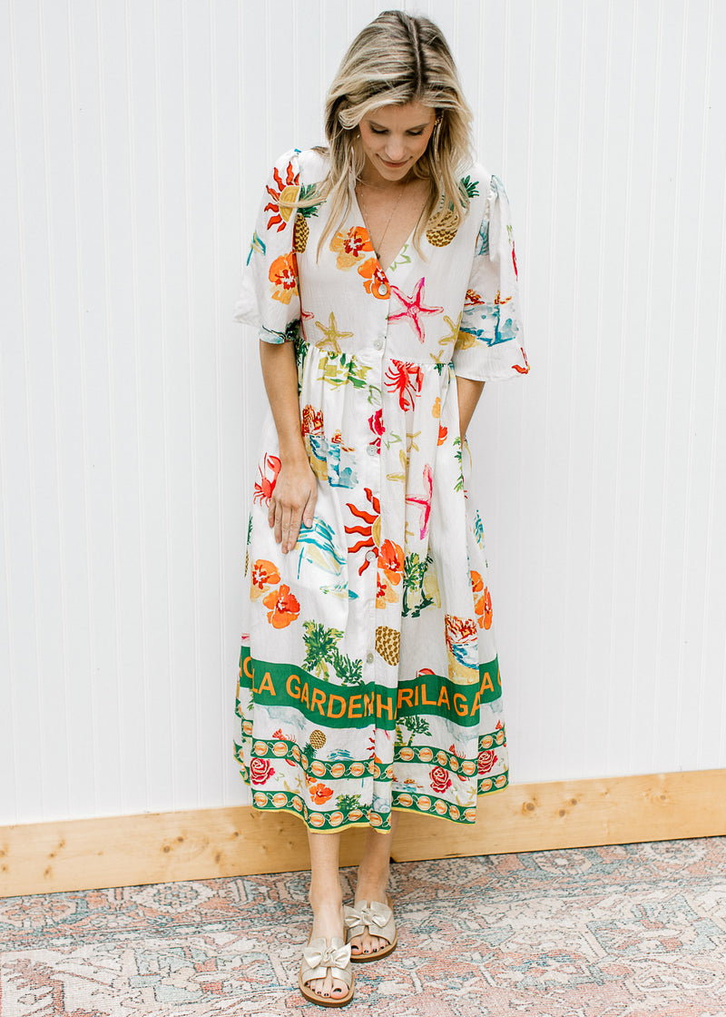 Model wearing a button up cream midi with av-neck and multicolored tropical pattern. 