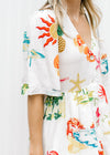 Close up on short sleeves on a button up cream midi with a multicolored tropical pattern. 