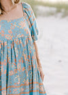 Close up view of square neck and bubble short sleeves on a light blue dress with gold floral pattern