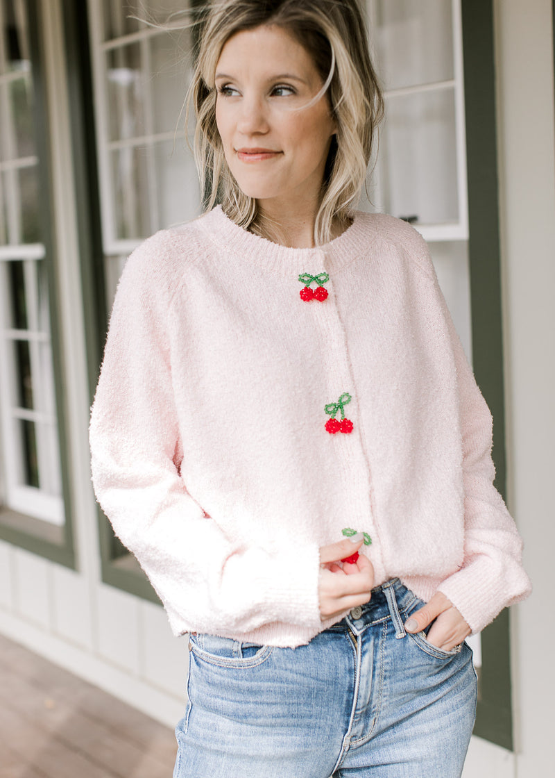 Model wearing a comfy pink cardigan with three cherry beaded clasp closure and long sleeves.