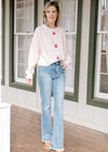 Model wearing jeans and a pink cardigan with three cherry beaded clasp closure and long sleeves.