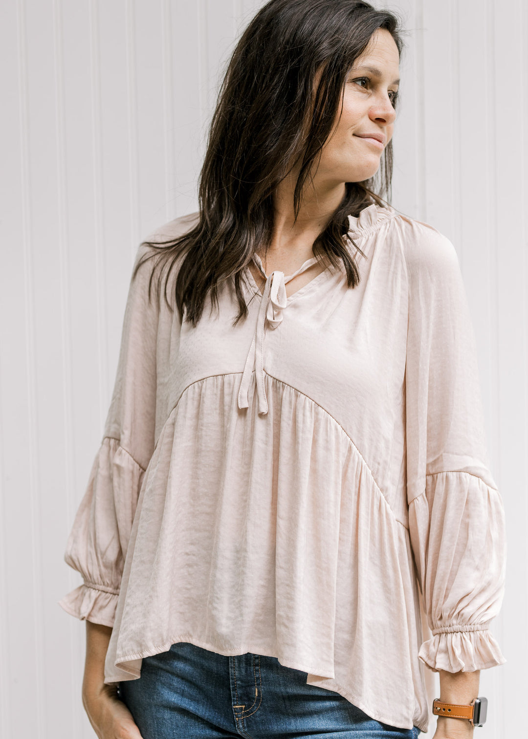 Model wearing a light pink polyester top with a babydoll fit and long sleeves with an elastic cuff. 