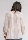 Back view of Model wearing a light pink top with a babydoll fit and long sleeves with elastic cuff.