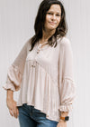 Model wearing a light pink v-neck top with a babydoll fit and long sleeves with an elastic cuff. 