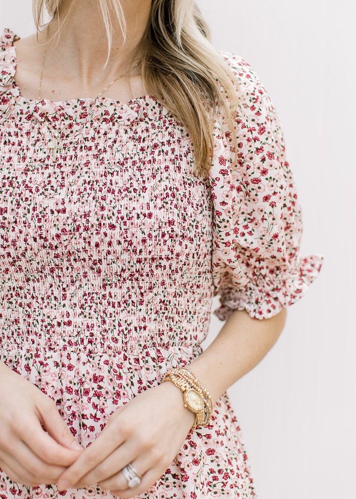 Close up of square neck, smocked bodice and short bubble sleeves on a cream midi with floral. 