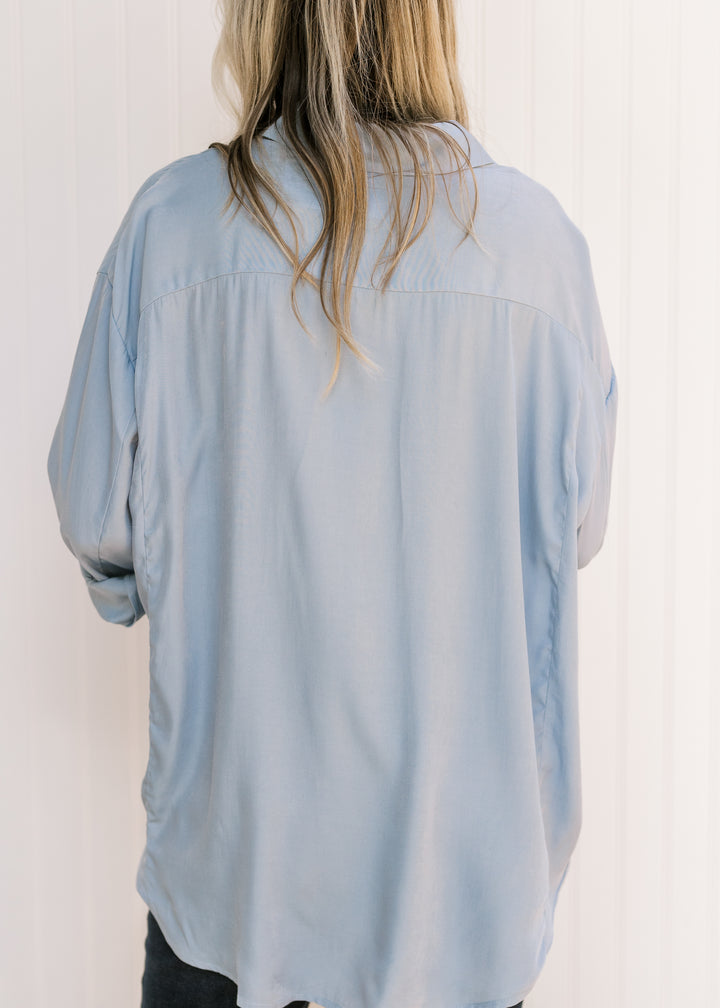 Back view of Model wearing a light blue button down with long sleeves, collar and patch pockets. 