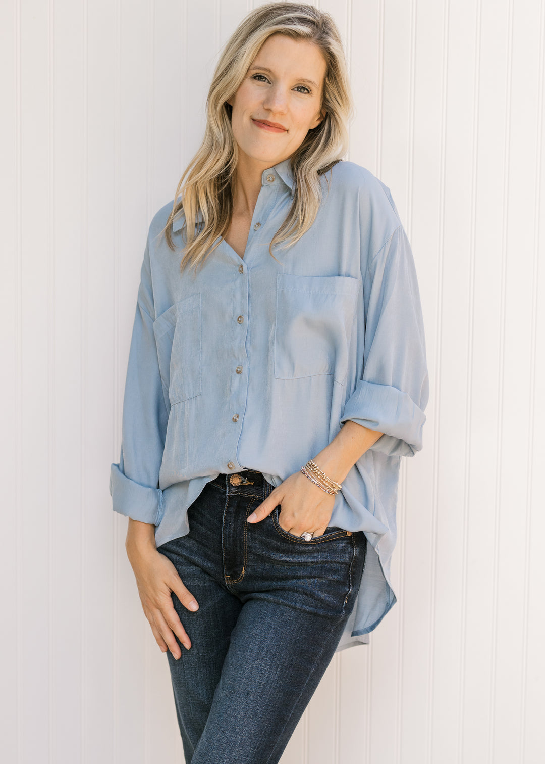 Model wearing a light blue button down with long sleeves, collar and two patch pockets. 