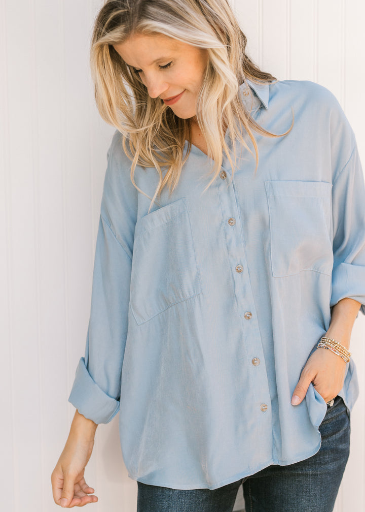 Model wearing a light blue button down with long sleeves, hi-low fit and two patch pockets. 