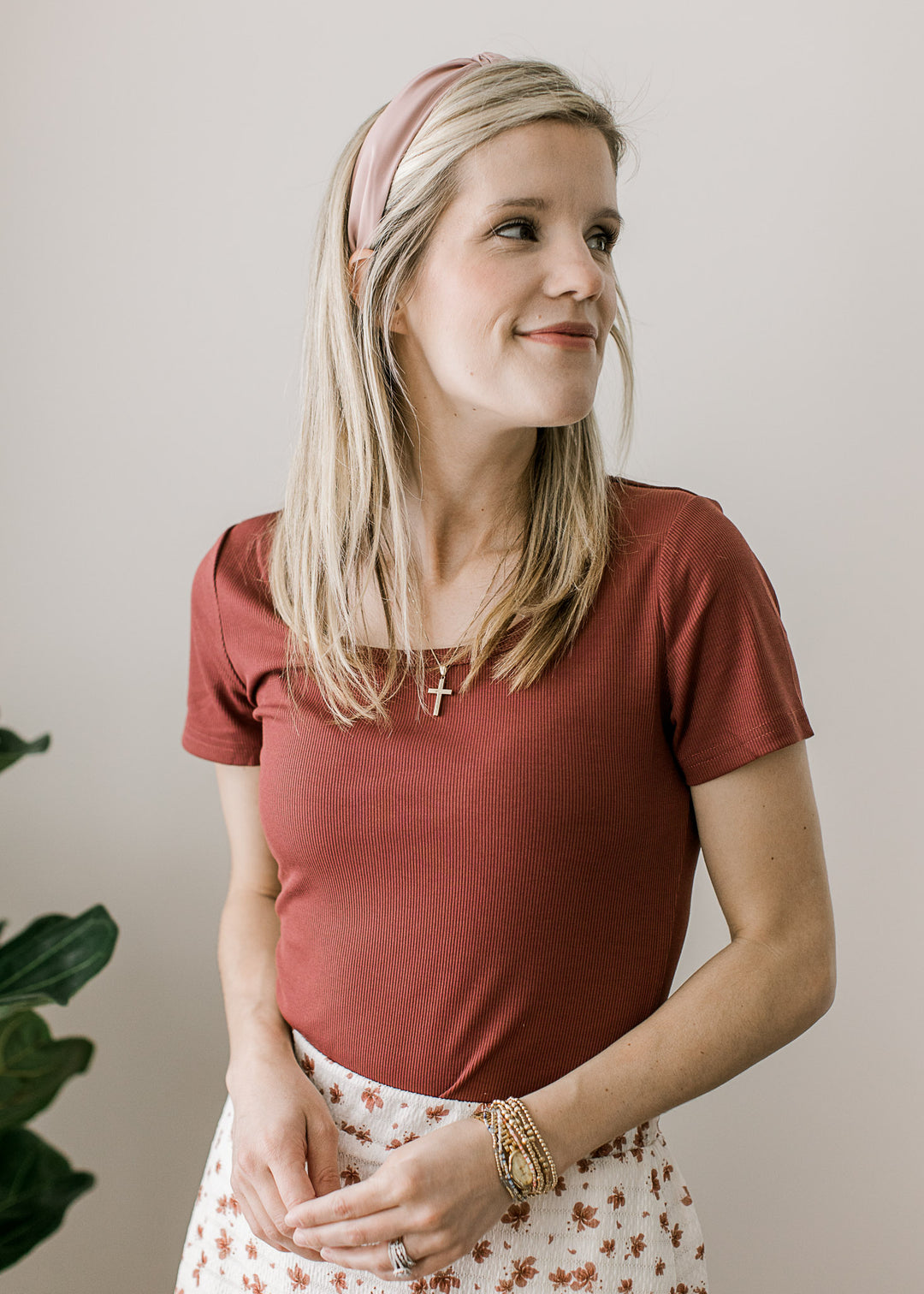 Model wearing a garnet rose colored top with short sleeves, scoop neckline and a ribbed fabric.