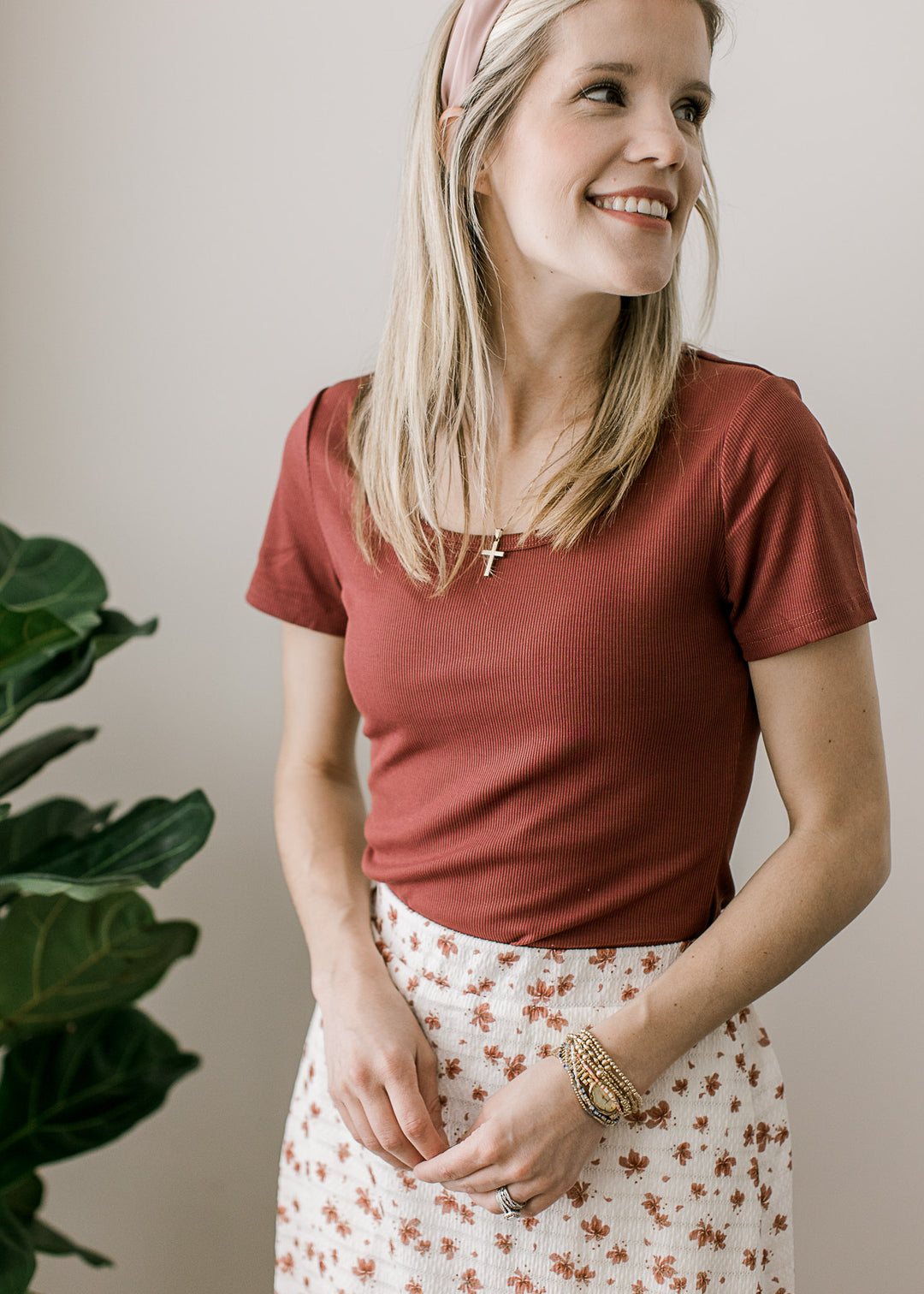 Model wearing a rose colored top with short sleeves, scoop neckline and a ribbed fabric.