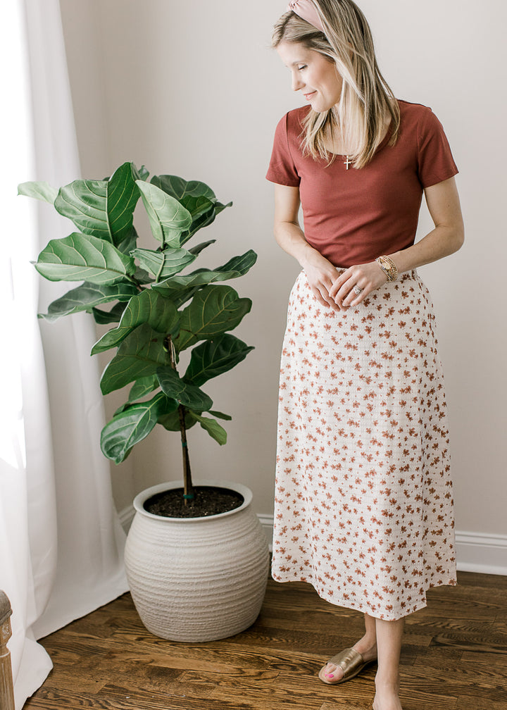 Model wearing cream midi skirt and a rose top with short sleeves, scoop neck and a ribbed fabric.