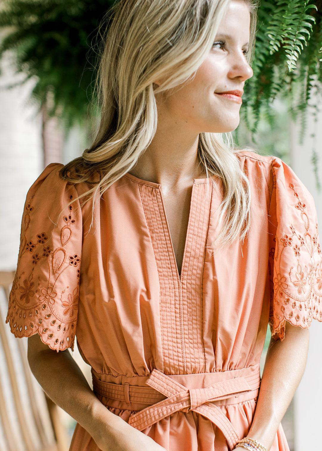 Close up of v-neck and tone on tone eyelets on a warm rust midi with short sleeves. 