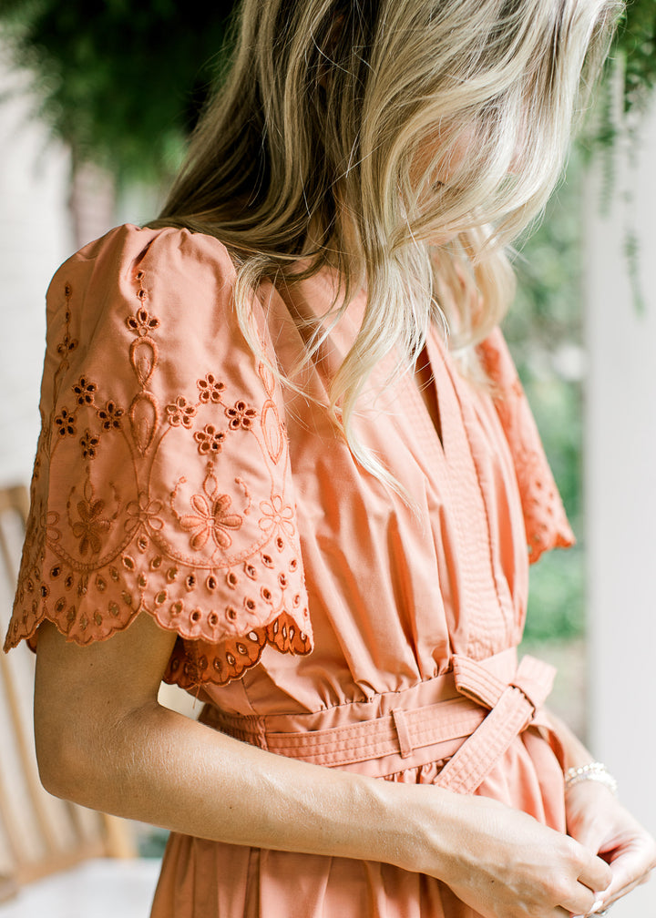 Close up of tone on tone embroidered eyelets along the short sleeve of a warm rust midi.