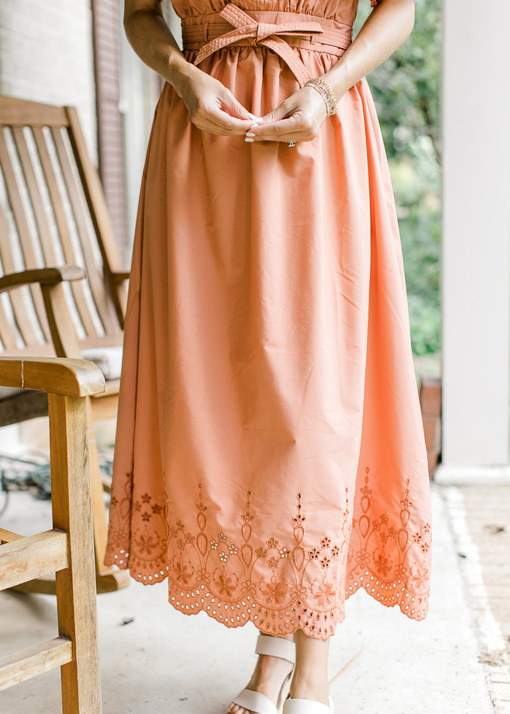Close up of tone on tone embroidered eyelets along the hem of a warm rust midi. 