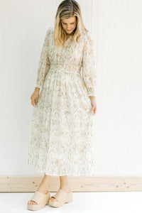 Model wearing wedges with a cream floral midi dress with elastic waistband and sheer long sleeves. 