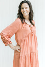 Close up of lantern long sleeves and v-neck with a tie on a salmon dress. 