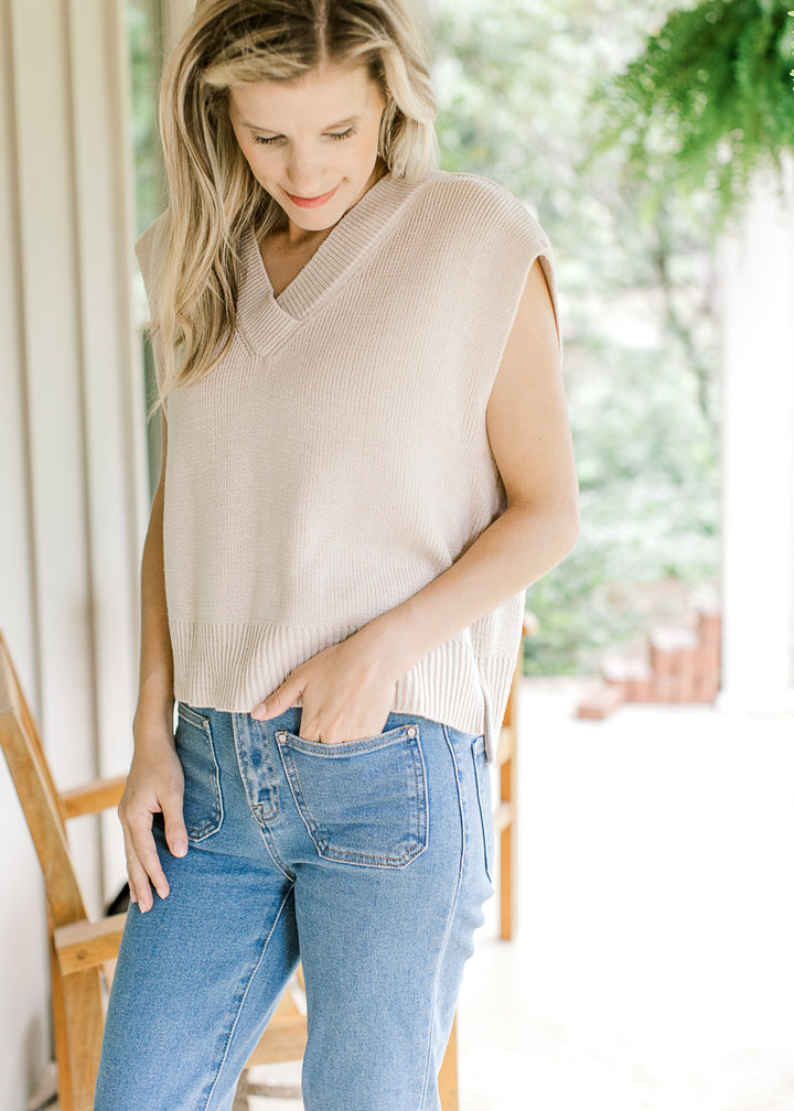 Mod wearing a cream ribbed sweater with capped sleeves, v-neck and ribbed neck and hem.