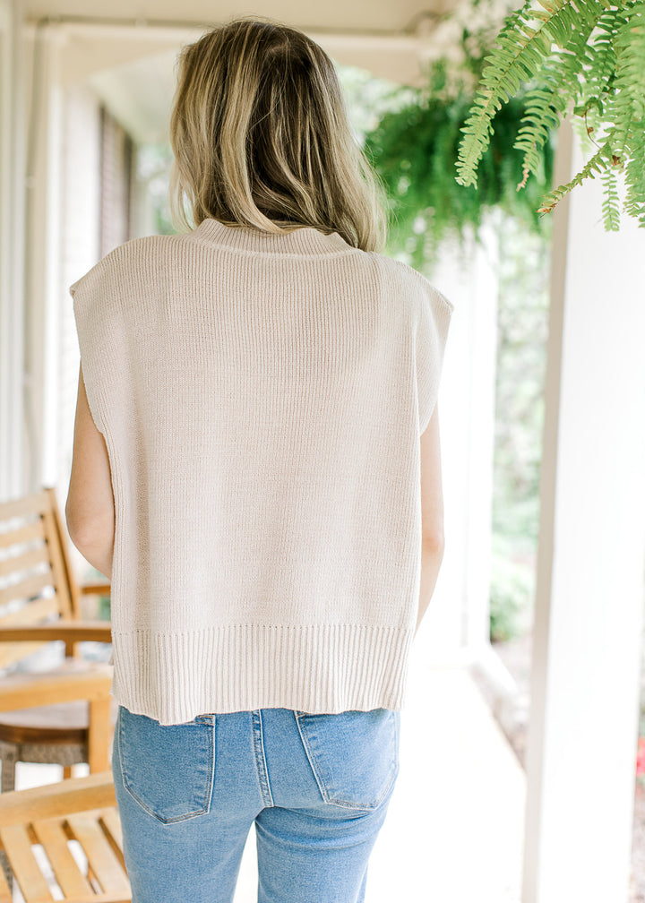 Back view of model wearing a cream capped sleeve sweater with a v-neck. 