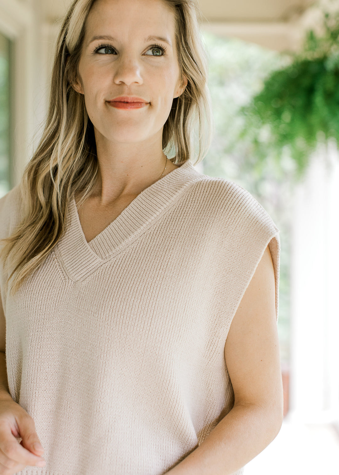 Close up of contraction ribbing at v-neck of a cream ribbed capped sleeve sweater. 