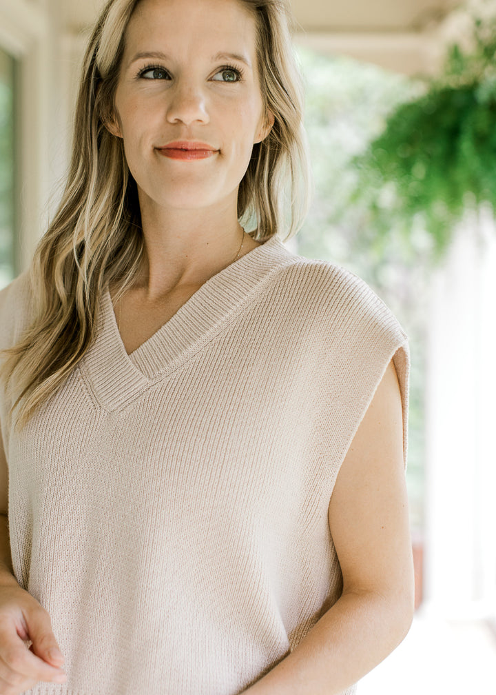 Close up of contraction ribbing at v-neck of a cream ribbed capped sleeve sweater. 
