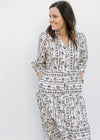 Model wearing a cream v-neck midi with a black floral design, pockets and 3/4 sleeves. 