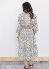 Back view of model wearing a cream midi with a black floral design, 3/4 sleeves and a v-neck. 