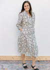 Model wearing black shoes and a cream midi with a black floral pattern and button front. 