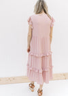 Back view of Model is wearing a blush colored midi with ruffled tiers and ruffle cap sleeves.