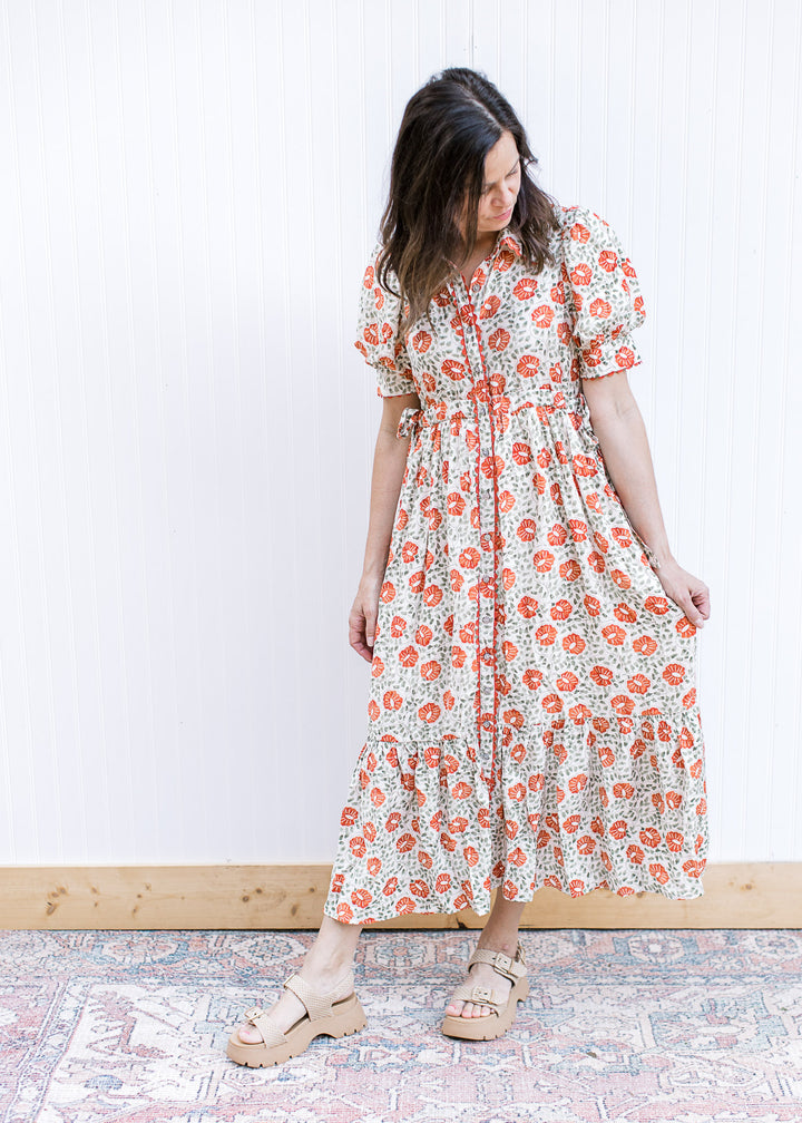 Model wearing sandals and a cream maxi with rust and green floral, button front and short sleeves. 