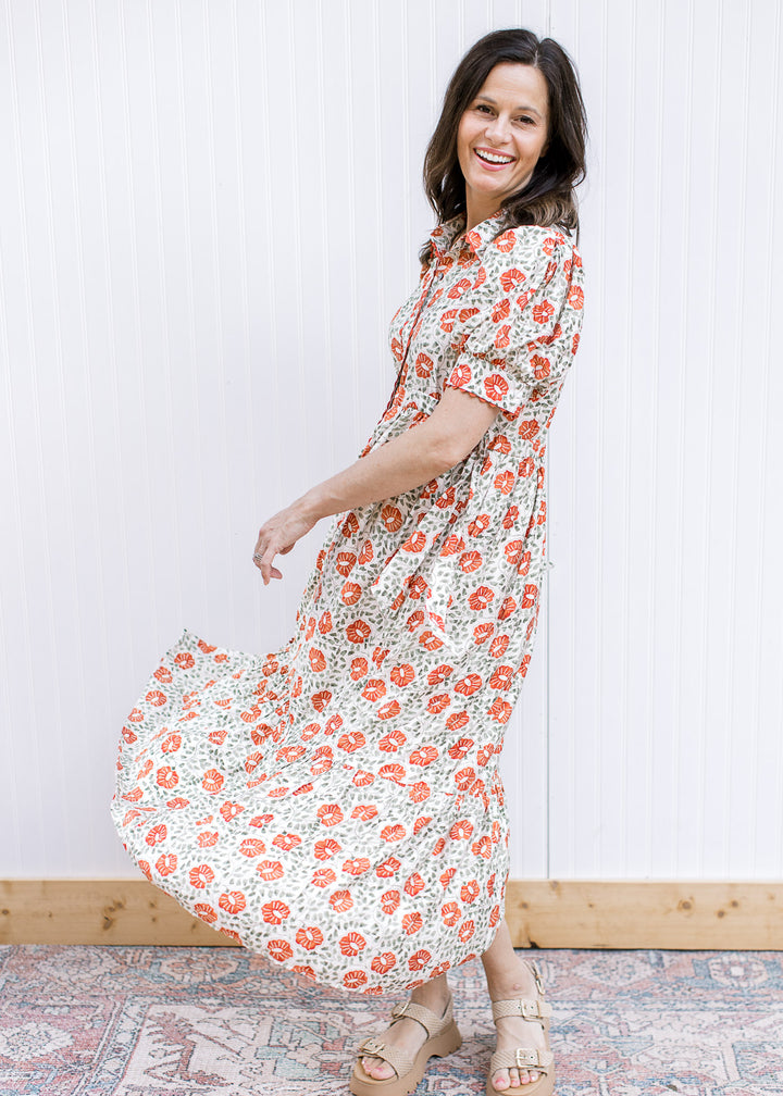Model wearing a cream maxi with rust and green floral, button front, short sleeves and side ties. 