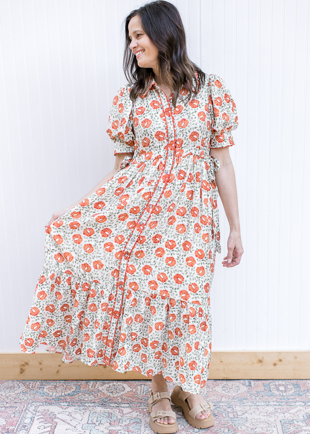Model wearing a cream flowy maxi with rust and green floral, button front and short sleeves. 