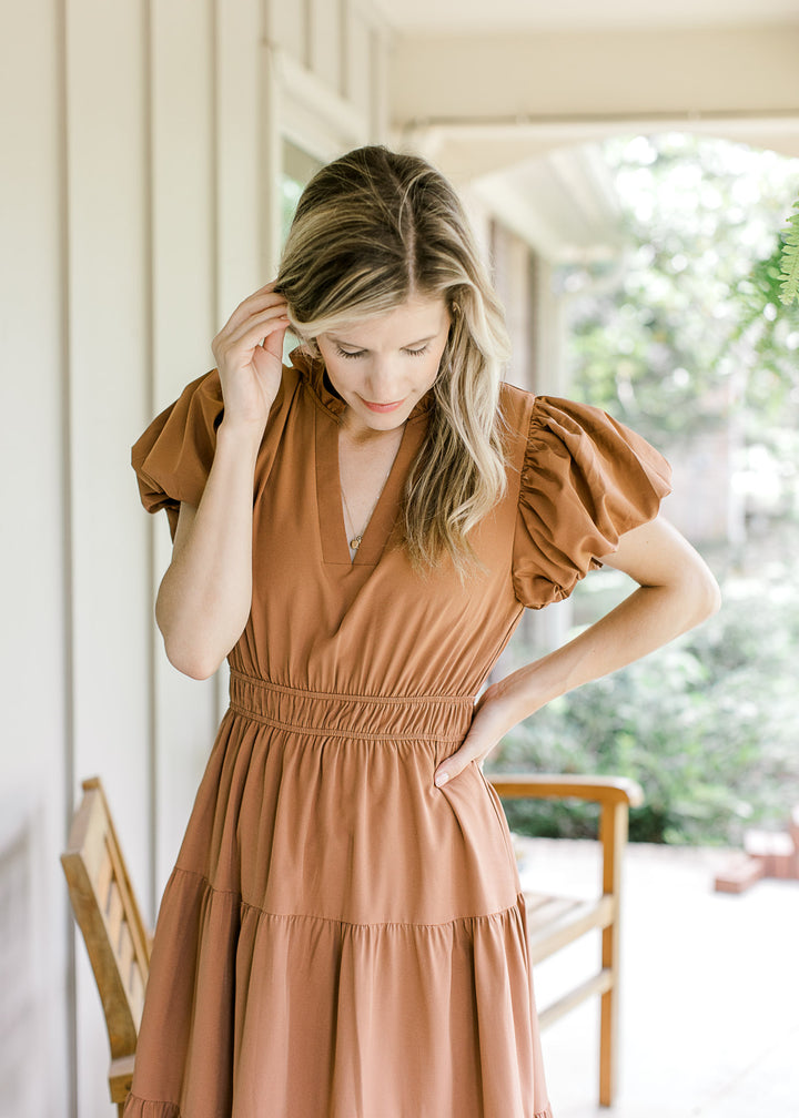 Close up of v-neck, elastic wasit and bubble short sleeves on a rust maxi. 