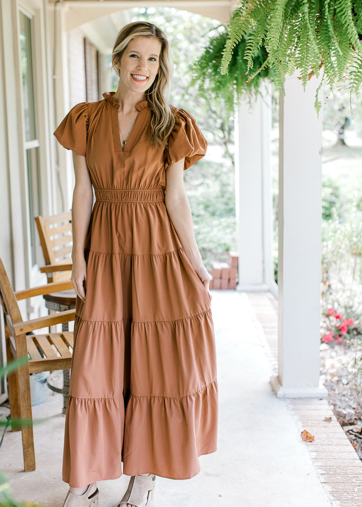 Model wearing wedges with a rust maxi with an elastic waist, bubble short sleeves and a v-neck.