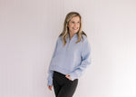 Model wearing a sky blue, slightly cropped  pullover with a 1/4 zip and long sleeves.