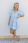 Model wearing a baby blue dress with lace lined tiers and bubble short sleeves. 