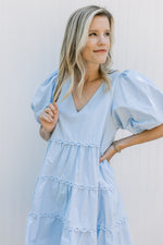 Close up of bubble short sleeves and v-neck on a baby blue above the knee dress. 