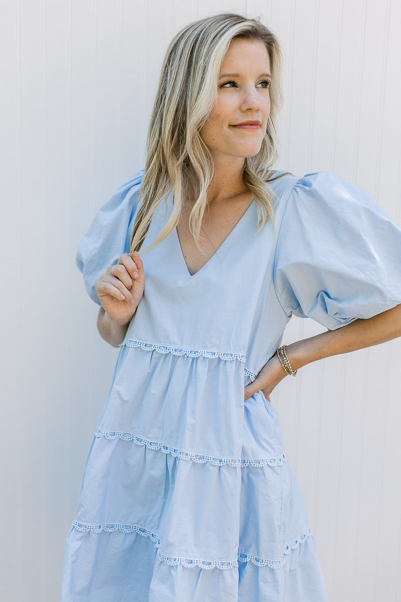 Close up of bubble short sleeves and v-neck on a baby blue above the knee dress. 