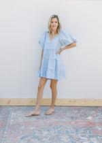 Model wearing a baby blue tiered dress with bubble short sleeves and a v-neck.