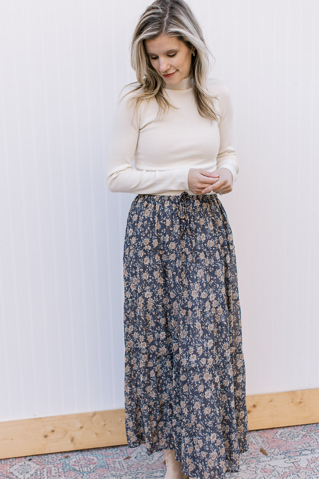  Model wearing a cream top and a slate blue midi with floral, elastic waist with tie and pockets. 