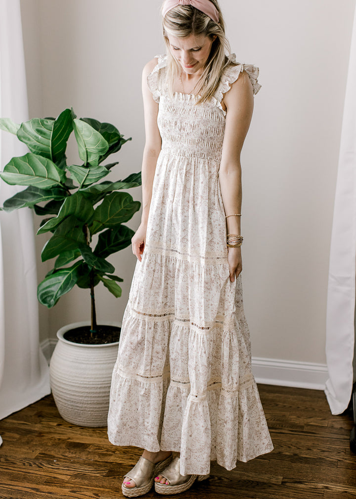 Model wearing a cream maxi with light brown bunny and floral, smocked bodice and ruffled straps.